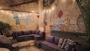 Un coin salon accueillant, avec des meubles en osier, un tapis à motifs et des guirlandes lumineuses.
