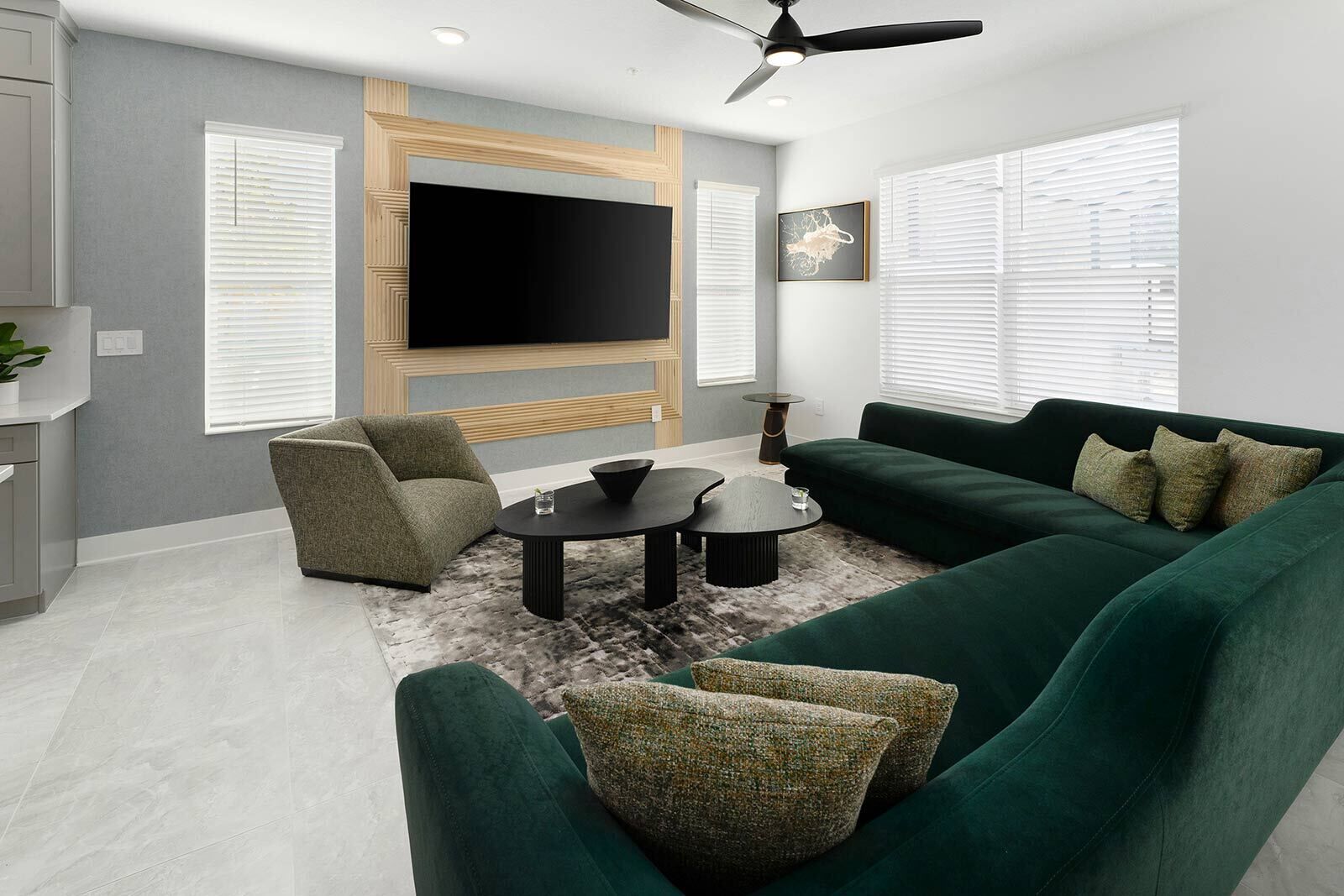 Una sala de estar moderna con un sofá verde, un sillón individual, una mesa de centro y un televisor de pantalla plana montado en la pared.