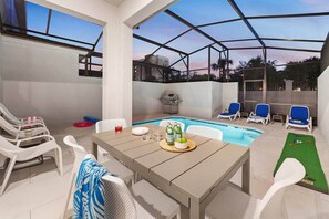 A covered outdoor area with a pool, lounge chairs, and a table with drinks and snacks. - Vor5340aa: 4 Bed, Foodie's Fantasy, Pool (Orlando)