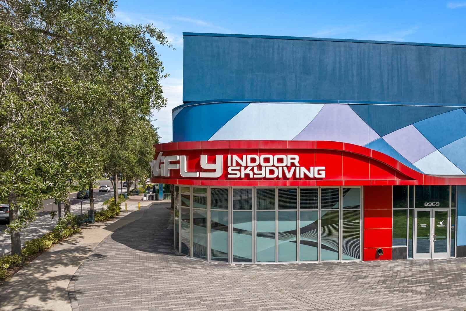 Un bâtiment à la façade rouge et bleue, sur lequel on peut lire l’inscription « FLY INDOOR SKYDIVING ».