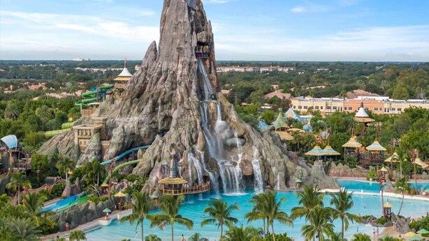 A large rock formation with a waterfall, a pool, and surrounding greenery. - Vor5432aa: 4 Bed, Dragon's Den, Pool (Orlando)