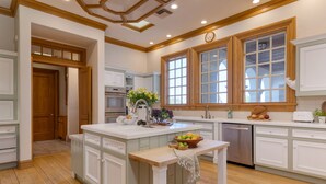 A spacious kitchen with wooden cabinets, a central island, and a large window.