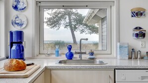 A kitchen with a window, a coffee maker, a bread loaf, and decorative plates. - "Bosilka" - 75m from the sea by Interhome (Hundested)
