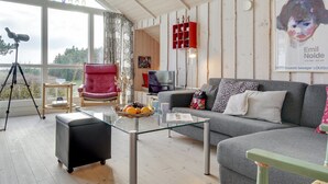 A living room with a red chair, grey sofa, and a glass coffee table. There's a telescope on a tripod, a red shelf, and a poster of Emil Nolde. - "Bosilka" - 75m from the sea by Interhome (Hundested)