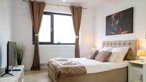 Ein Schlafzimmer mit Bett, Nachttisch, Lampe und einem Bild an der Wand.