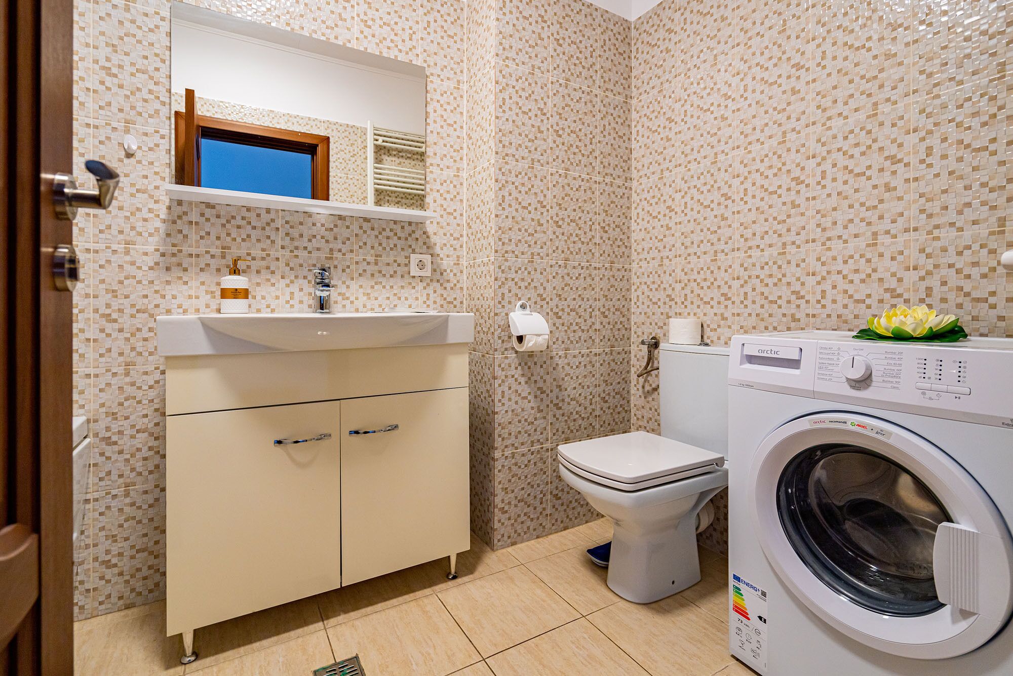 A compact bathroom with a sink, toilet, and washing machine.