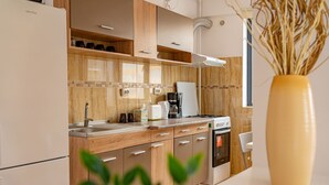 Eine moderne Küche mit Holzausstattung, einem eingebauten Backofen, einer Kaffeemaschine und einer großen Vase mit Trockenblumen.
