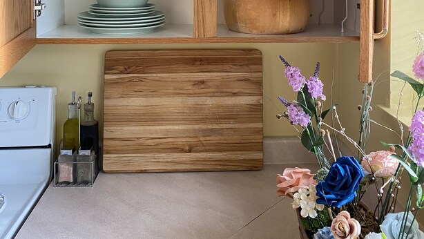 A kitchen with a wooden cabinet, a countertop with a cutting board, and a vase of flowers. - Clean safe double bedroom, comfy bed, keyless entry, no stairs, on bus routes (Langley Township)