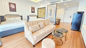 Una habitación de hotel moderna con una cama grande, un sofá, una mesita redonda y un refrigerador.