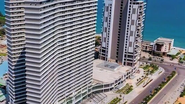 Un hotel de gran altura con varios balcones, un patio central y vista al mar.