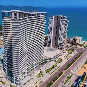 Ein Hochhaus-Hotel mit mehreren Balkonen, einem Innenhof und Blick aufs Meer.