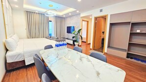 Una habitación de hotel con cama, una mesa de comedor con sillas, un televisor y un armario.