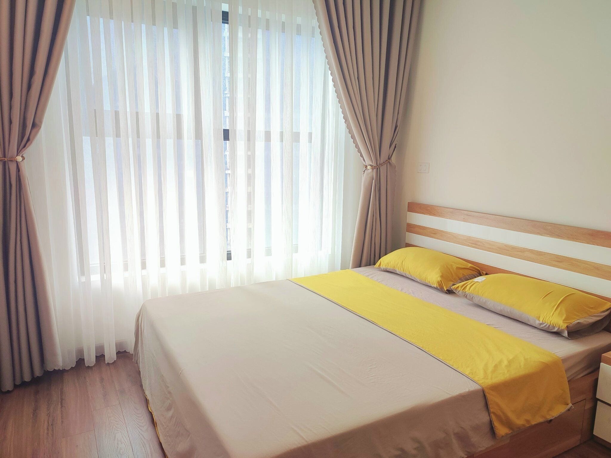 A hotel room with a bed, curtains, and a window.