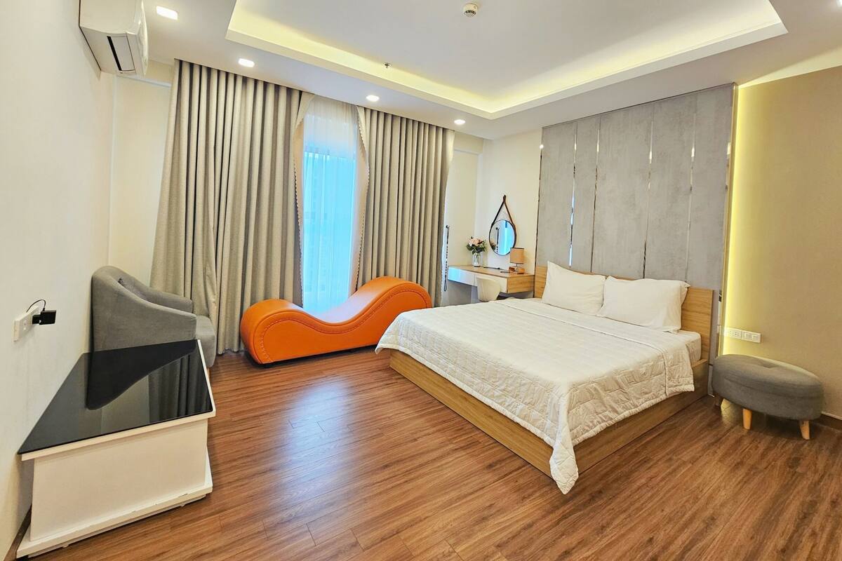 A modern hotel room with a large bed, a desk, and a comfortable seating area.