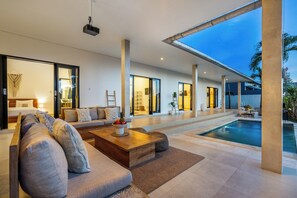 A modern living room with a sofa, coffee table, and a pool area.