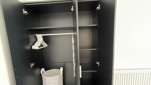 A black wardrobe with open doors, featuring multiple shelves and hanging space.