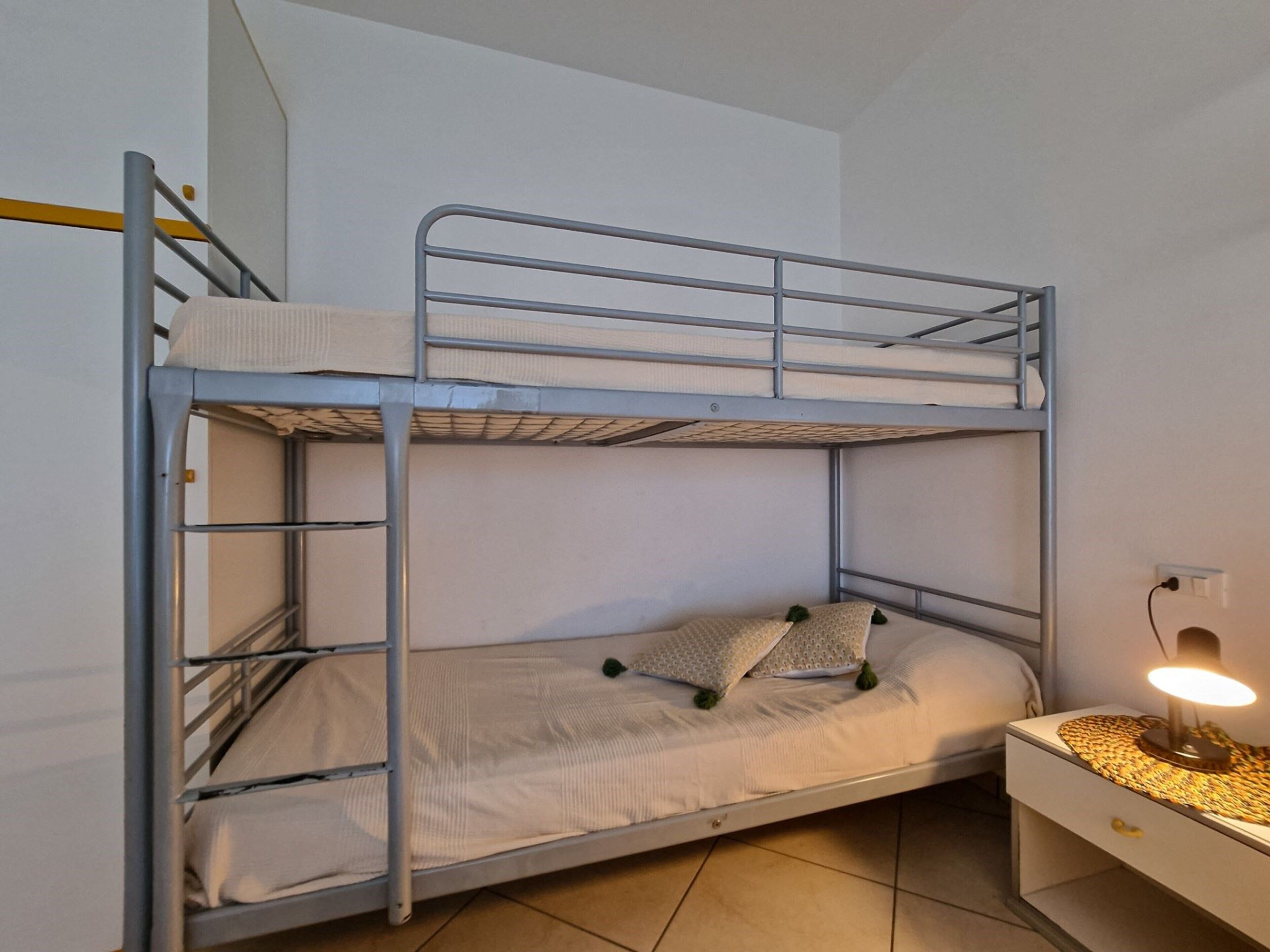 A bunk bed with a desk and a lamp.