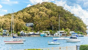 A marina with boats docked, surrounded by a forested hill and residential buildings. - Stay 3 nights, pay 2 this Winter* (BOOKER BAY)