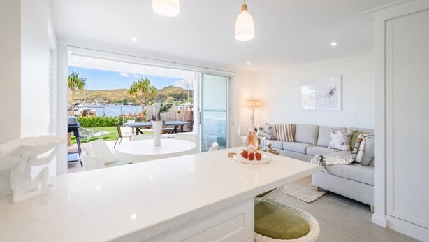 A modern kitchen with a large island, a dining area with outdoor seating, and a view of a lake. - Stay 3 nights, pay 2 this Winter* (BOOKER BAY)