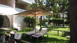 Une cour avec deux fauteuils de jardin, un vélo et un espace salon abrité.