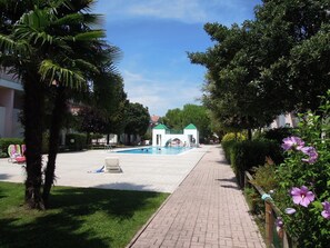Ein Poolbereich mit blauem Himmel, einem Weg und einem Gebäude mit Gründach im Hintergrund.