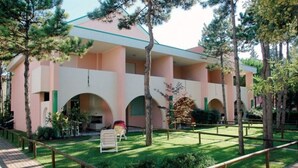 Un bâtiment à la façade rose, doté de nombreuses arcades et surmonté d’un toit végétalisé.