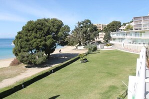 A coastal hotel with a grassy lawn, trees, and a view of the sea.