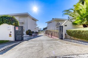 A gated residential area with white buildings, a clear sky, and a palm tree.