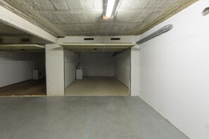 An underground parking garage with concrete walls, a flat floor, and a ceiling with visible pipes and vents.