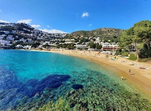 Un poble costaner amb aigües blaves cristal·lines, platges sorrenques i edificis blancs.
