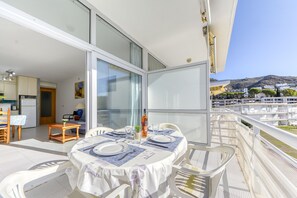 Ein Balkon mit Esstisch, Blick auf eine Wohngegend mit Gebäuden und einem Berg in der Ferne.