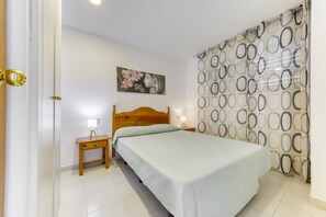 Ein Schlafzimmer mit einem Bett, Nachttischen, einer Wandleuchte und einem Gemälde.