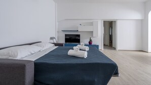 A modern hotel room with a large bed, a flat-screen TV, a desk, and a small potted plant. - Appartamento Ecate (Ragusa)