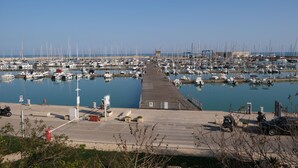 A marina with numerous boats docked, a long pier, and a clear sky. - Appartamento Ecate (Ragusa)