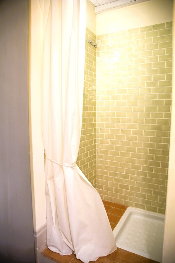 A bathroom with a shower, tiled walls, and a white curtain.