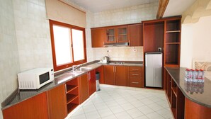 Une cuisine avec des meubles de rangement en bois, un four à micro-ondes, un réfrigérateur et un évier.