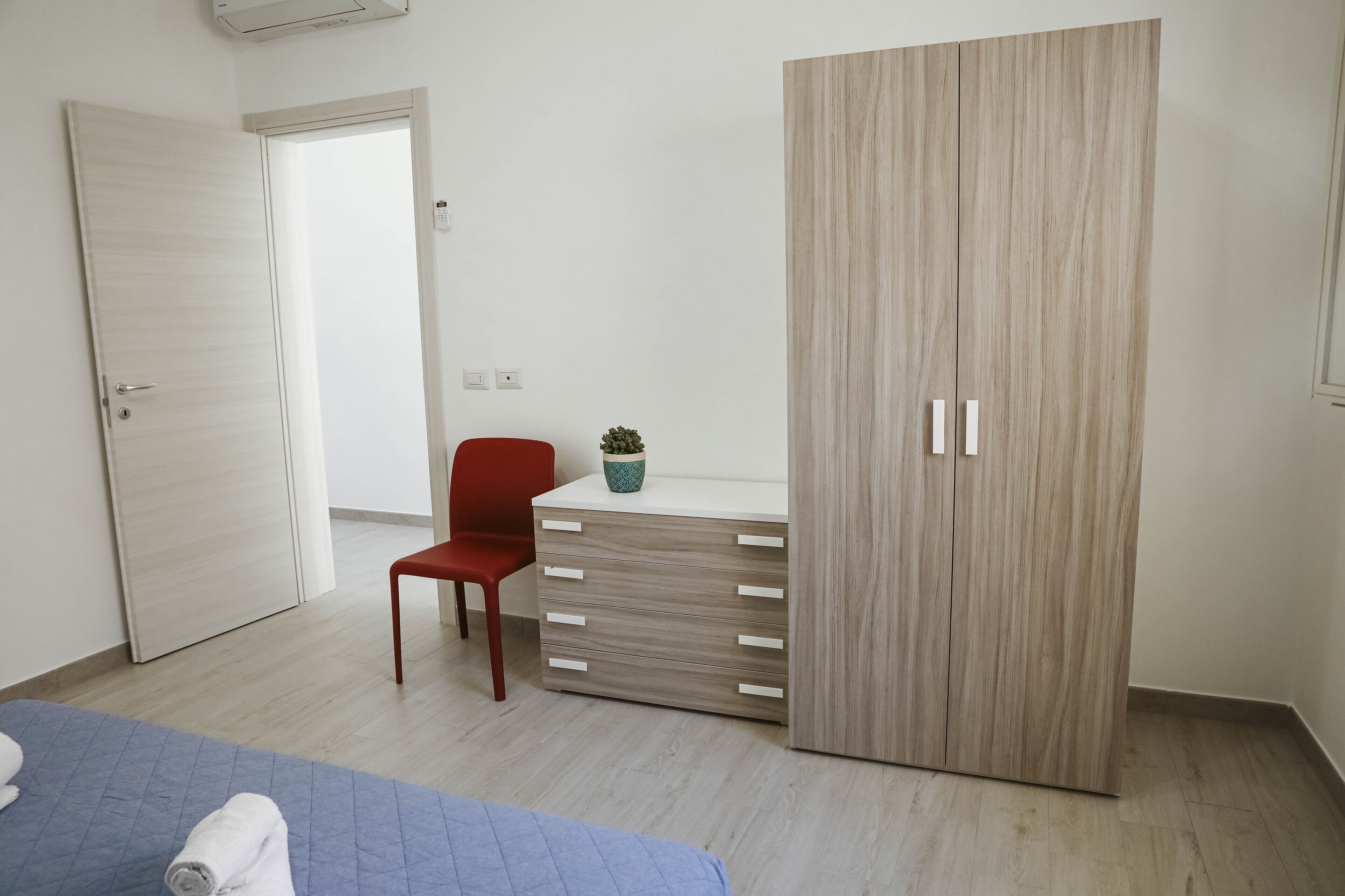 A bedroom with a bed, a desk, a chair, and a wardrobe.