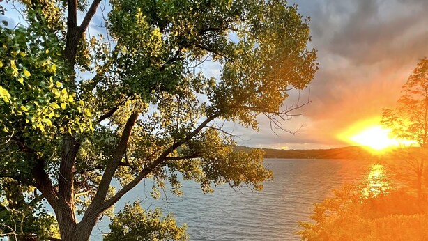 A tree-lined pathway leading to a body of water with a sunset in the background. - The Lake House on Otisco Lake, stunning family getaway (Marietta)