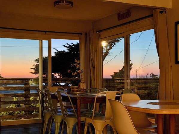 A dining area with a table and chairs, large windows with a view of the sunset, and a sign that reads 'Bistro'.