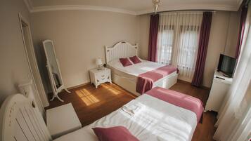 A hotel room with two beds, a TV, a mirror, and a bedside table.