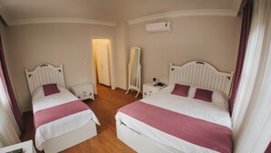 Et hotelværelse med to senge, et klædeskab, et sengebord, et spejl og en vægmonteret aircondition.