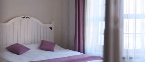 A bedroom with a bed, curtains, and a window.