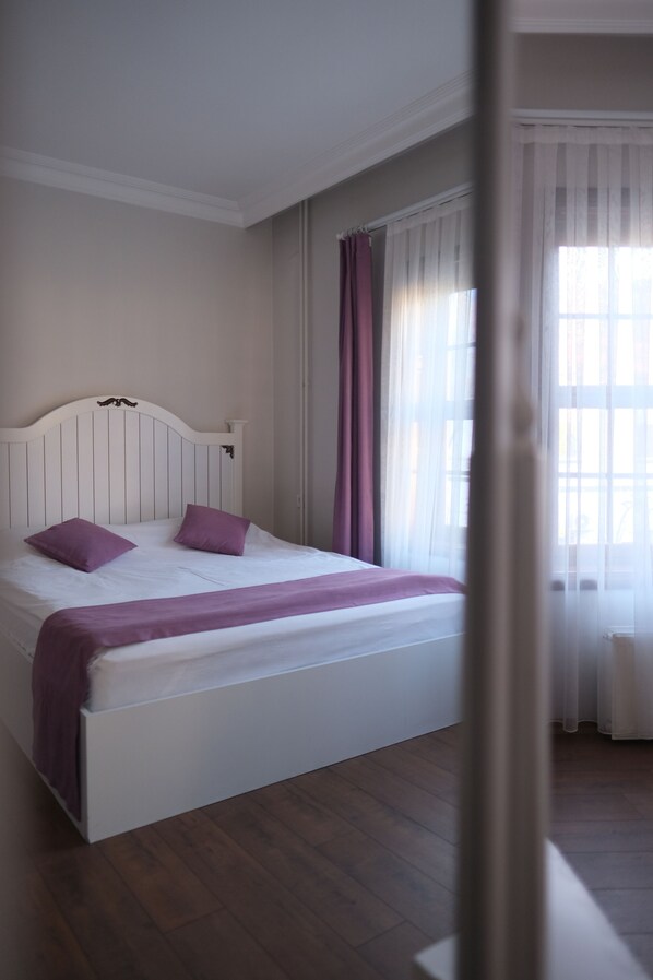 A bedroom with a bed, curtains, and a window.