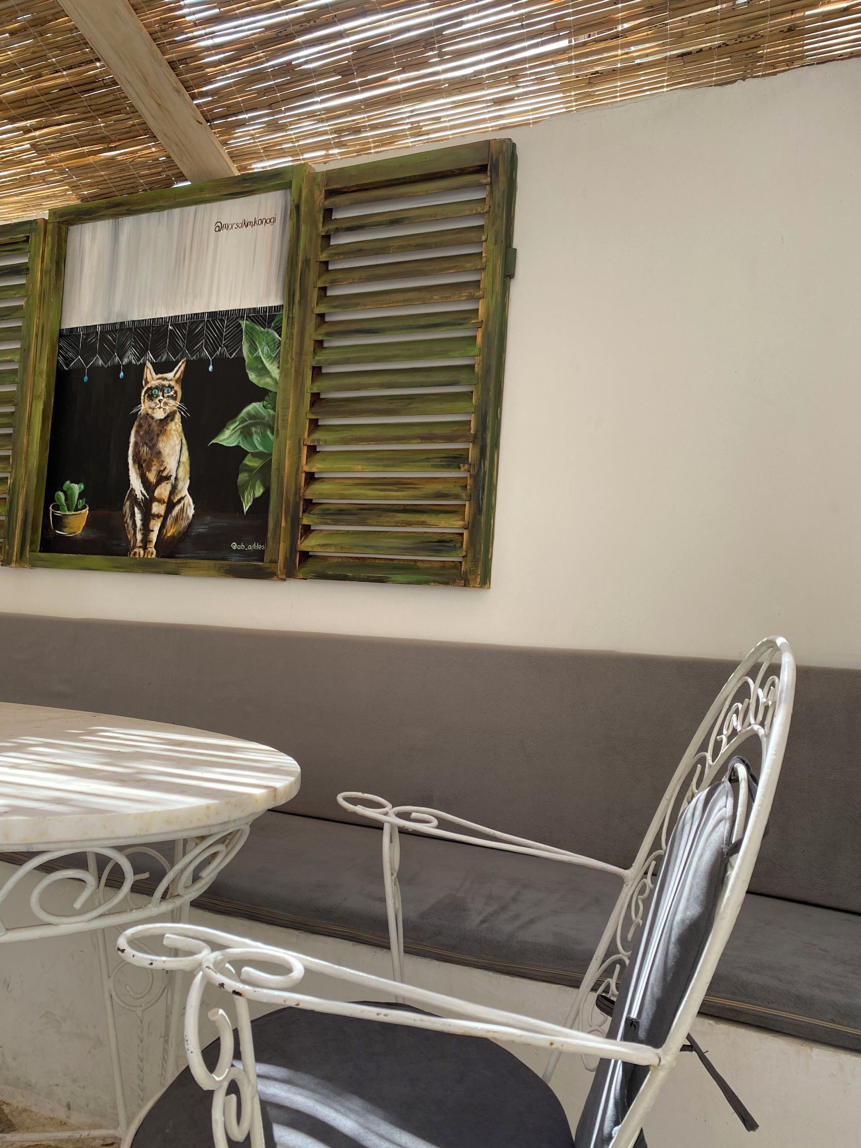 Uma área de refeições com mesa e cadeiras, um sofá e um quadro de gato fixado na parede.