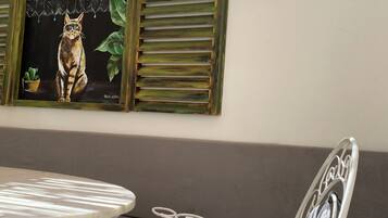 Uma área de refeições com mesa e cadeiras, um sofá e um quadro de gato fixado na parede.