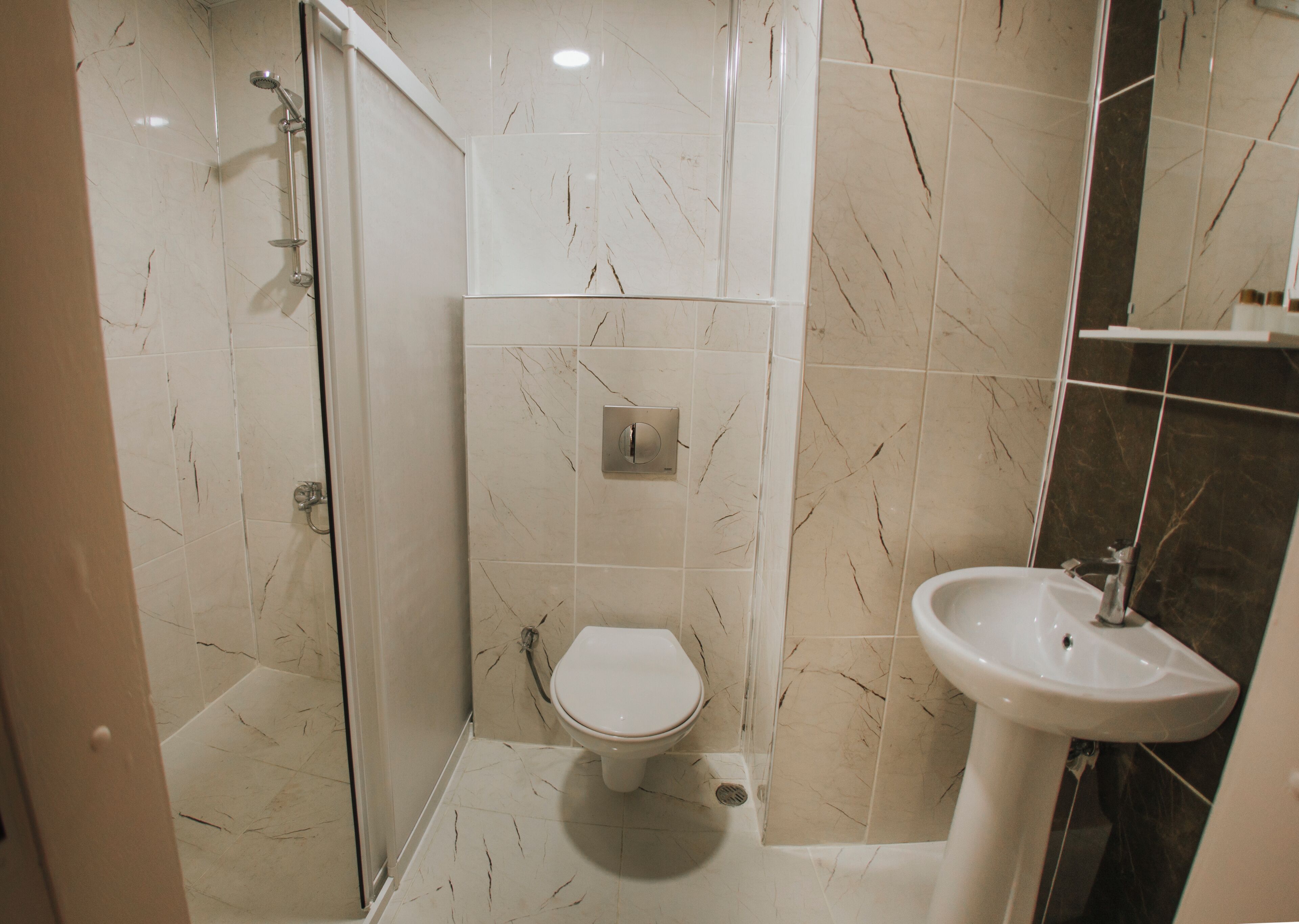 Un baño con inodoro, lavabo y zona de ducha.