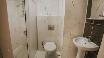 Un baño con inodoro, lavabo y zona de ducha.