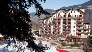A multi-story hotel with balconies, ski slopes in the background, and a mountainous landscape. - Renovated apartment in La Tania center with parking (Courchevel)