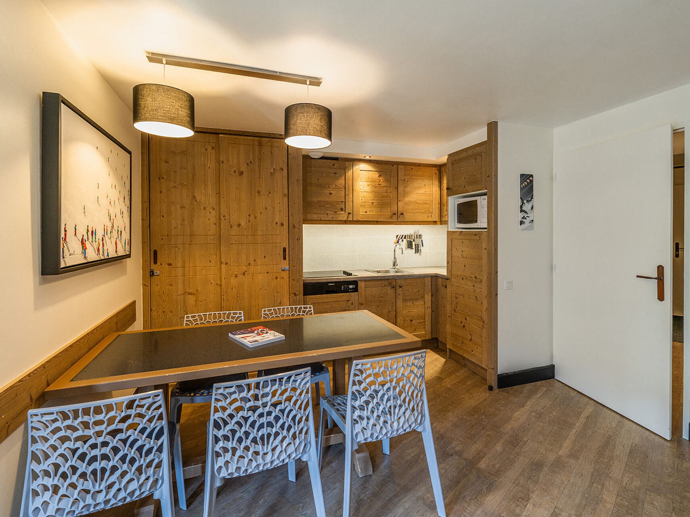 Een moderne keuken met houten kastjes, een eettafel en witte stoelen.