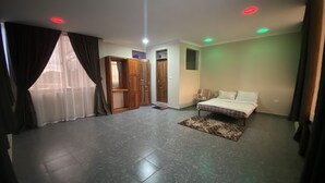 A room with a bed, a small rug, a door, and a window with curtains.